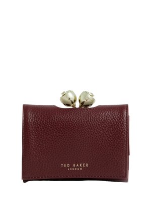 Portefeuille en cuir texturé bordeaux avec fermoir floral doré et logo "Ted Baker London" embossé en or sur le devant.