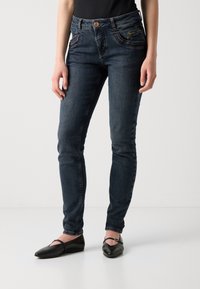 Dark blue skinny jeans with five pockets, a button closure, and stitched detailing along the front pocket edges. Smooth denim texture.