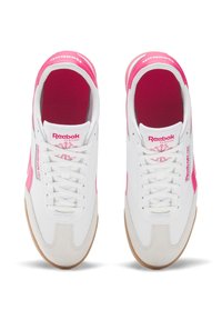 Reebok klassiset lenkkarit valkoisina, joissa on vaaleanpunaiset yksityiskohdat. Ne ovat valmistettu sileästä nahasta, kumipohjasta ja niissä on pehmustettu sisäosa mukavuutta varten.