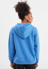 Sudadera de forro polar azul con una capucha grande, puños y dobladillo acanalados, y un ajuste relajado. Textura suave con un color sólido y sin patrones visibles.