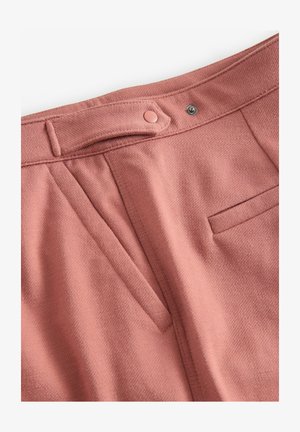 Rosenfarbene Hose aus strukturiertem Stoff, mit einer vorderen Tasche und einem Knopfverschluss. Falten verleihen der Taille Volumen.