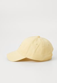 Casquette de baseball jaune avec une visière courbée, fabriquée en coton, dotée d'une broderie minimaliste à l'avant et de trous de ventilation sur les côtés.