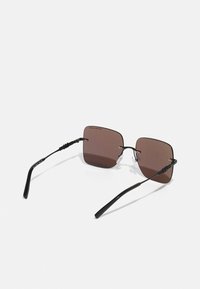 Ochelari de soare pătrati cu rame subțiri negre, lentile de culoare brună, suporturi pentru urechi texturate și elemente hardware minime.