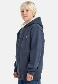 Felpa con zip color navy, foderata in morbido fleece bianco, con polsini elastici e grandi tasche frontali; presenta il logo "Billionaire" ricamato in bianco.