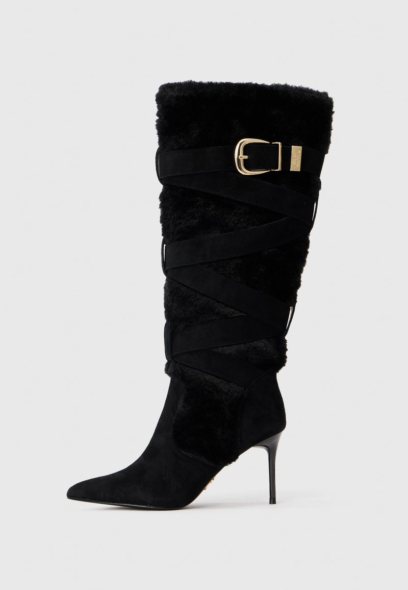 Stivale nero in suede fino al ginocchio con parte superiore in pelliccia sintetica piegata, cinturini decorativi avvolgenti e dettagli in fibbia dorata.