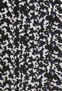 Tissu noir avec un motif dispersé de formes blanches et bleues, présentant une surface texturée avec des formes et des tailles variées.