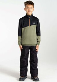 Grüne und schwarze Zip-Jacke mit orangefarbenem Reißverschluss, langen Ärmeln und Logo. Kombiniert mit schwarzen Hosen und grauen Schuhen. Glatte Stofftextur.
