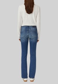 Dunkelblaue Jeans aus Denim im Bootcut-Design. Mit fünf Taschen und einer mittelhohen Taille. Die Rückansicht zeigt Nähte und Ausbleichdetails.