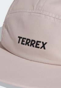 Casquette rose clair en tissu lisse, dotée d'un design structuré et d'un logo noir "TERREX" à l'avant. Surface texturée visible.