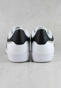 Sneakers bianchi in pelle con un tallone testurizzato nero e suola in gomma bianca. Ventilazione sui lati, finitura liscia e collare imbottito.