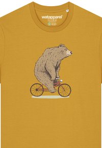 Mosterdgele T-shirt met een illustratie van een beer die op een rode fiets rijdt. Het ontwerp heeft omlijnde details en een speelse uitstraling op de beer.