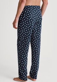 Navyblauwe pyjamabroek met een elastische tailleband, voorzien van een herhaald patroon van lichtgroene flesafdrukken door het hele kledingstuk.