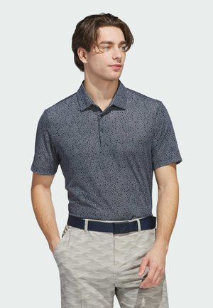 Navy short-sleeve polo shirt with a subtle pattern, collar, and button placket, paired with light gray patterned trousers and a dark belt.