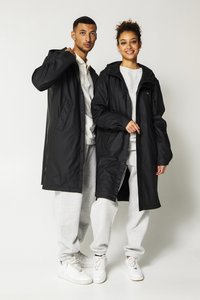 Black waterproof coats with hoods, two front pockets, and button closures, paired with gray sweatpants and white sneakers.
