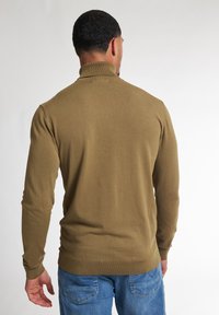 Olivově zelený svetr s dlouhým rukávem a vysokým límcem, vyrobený z hladkého pleteného materiálu, se přiléhavým střihem a žebrovanými manžetami.