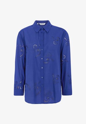 Camicia blu a maniche lunghe con collo classico, caratterizzata da motivi ricamati con ritagli e bottoni sul davanti. Tessuto liscio e leggero.