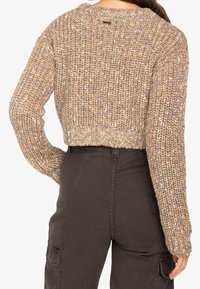 Pull court en maille dans différents tons de brun, rose et crème. Il présente des poignets et un ourlet côtelés, un col rond et un tissu texturé.