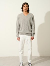 Grå v-ringad tröja med lång ärm, parat med vita jeans och mönstrade sneakers. Slät textur med en avslappnad passform.