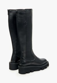 Knee-high black leather boots with side zippers, textured sides, a chunky tread sole, and a smooth finish. Features raised stitching accents.