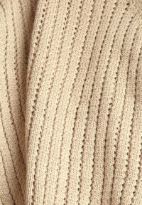 Gestrickter Pulloverstoff in hellbeiger Farbe mit vertikalen Streifen und Lochmustern, weiche Textur und gemütliches Aussehen.