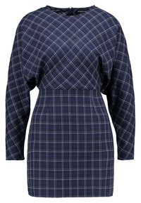 Marinblå klänning med rutmönster, med långa ärmar, rund halsringning och en figurnära midjedesign. Texturerad tyg med vita accenter.