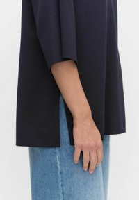 Marineblauwe, textuur geverfde top met korte mouwen. Zijsplitten en een oversized pasvorm, gecombineerd met lichtblauwe denim. Eenvoudig en modern ontwerp.