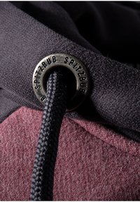 Kapuzenshirt aus einem dunklen Stoff mit strukturiertem Finish. Enthält ein Metallöhr mit eingravierter Markenbeschriftung und eine geflochtene Zugkordel.