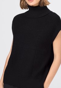 Svart stickad ärmlös polokrage-topp med ribbat mönster, med vertikala mönster och en bred krage; åtsittande vid fållen.
