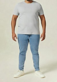 Šedé tričko s krátkými rukávy a kulatým výstřihem, v kombinaci s modrými úzkými džíny a bílými teniskami. Hladká látka, ležérní střih, minimalistický design.