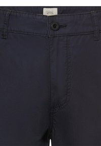 Donkerblauwe broek met knoopsluiting, riemlussen en zichtbare naden, met een "camel active" label aan de binnenkant van de tailleband.