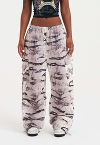 Lekkie, szerokie spodnie cargo w kolorze beżowym z szarym tie-dye i nadrukami motyli, z elastycznym pasem i kieszeniami po bokach.