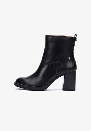 Bottine en cuir noir avec un bout rond, des détails de couture sur les côtés et un talon épais. Fermeture éclair à l'arrière pour un enfilage facile. Texture lisse.