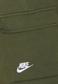 Nike Sportswear CLUB CARGO - Calças de fato de treino - rough green/white