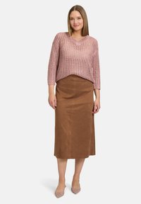 Jasnoróżowy sweter z otwartym splotem i rękawami 3/4, w połączeniu z brązową spódnicą midi i różowymi butami na szpilkach. Prosty i teksturowany wzór.