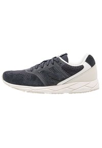 Námořnické semišové a síťované sportovní boty s bílými akcenty, plochými tkaničkami a polstrovanou podrážkou. Na boku je logo "N".