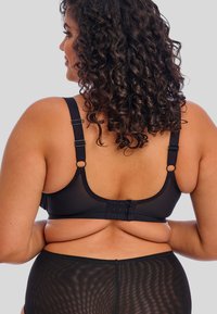 Reggiseno nero con spalline regolabili, materiale testurizzato e chiusura a gancio e occhiello sul retro, che mette in risalto una silhouette liscia.
