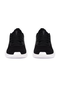 Mustad mustad jalatsid, millel on võrgukangas, valged kummist tallad, lamedad paelad ja minimalistlik disain, millel on väike logo keeles.