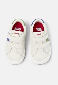 Weiße Lederschuhe mit Klettverschlüssen. Akzente in Grün und Blau nahe der Ferse. Rote Innensohle mit den Aufschriften "CAMPER" und "TWINS". Runde Zehenform.