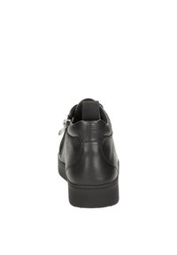 Zapato de cuero negro con textura suave, forma redondeada, detalle de cremallera trasera y suela de goma, diseñado para uso casual.