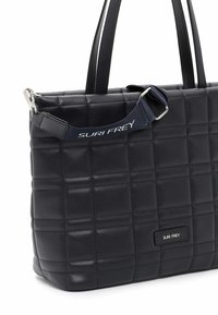 Námořnická modrá kabelka vyrobená z prošívané kůže. Má dvojité ucha a odnímatelný popruh. Stříbrné kovové doplňky zobrazují název značky.