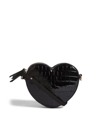 Black heart-shaped bag made of glossy, crocodile-embossed material. Features a zip closure and a detachable strap with tassel accents.