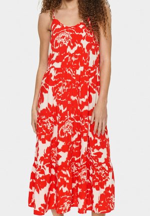 Vestido de flores en tonos rojo y blanco con tirantes finos, diseño en capas, tela ligera y silueta fluida.