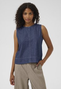 Denim ærmeløs top i mørkeblå med en rund halsudskæring og en løs pasform. Har kontrasterende syninger og en lige kant.