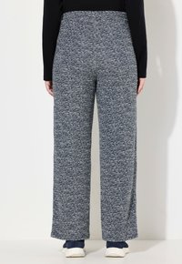 Donkerblauwe, gestructureerde wijde broek met een subtiel wit gespikkeld patroon, voorzien van een elastische tailleband en een ontspannen pasvorm.