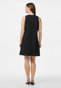 Juoda be rankovių suknelė su tiesia siluetu, turinti užpakalinį užtrauktuką ir glotnią tekstūrą, kirpta virš kelių.