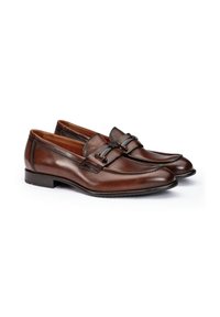 Brown leather loafers with a smooth finish, featuring a decorative strap and buckle detail. Low heel and rounded toe design.