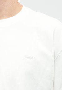 Λευκό βαμβακερό t-shirt με στρογγυλή λαιμόκοψη που διαθέτει μια διακριτική ανάγλυφη λογότυπο "Hollister" στο στήθος, με κοντά μανίκια και άνετη εφαρμογή.