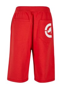 Red athletic shorts made from soft fabric, featuring an elastic waistband, side pockets, and a large white logo on the back pocket.