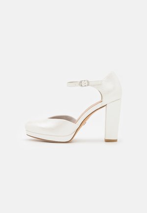 Chaussures à talons hauts blanches avec une finition texturée, bout rond, bride de cheville avec boucle, et un talon épais. Comprend une semelle patio.
