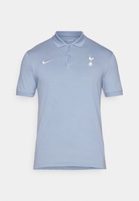 Lyseblå polo skjorte med krave, korte ærmer og Nike-logo. Har et Spurs emblem på venstre brystområde. Blød tekstur.
